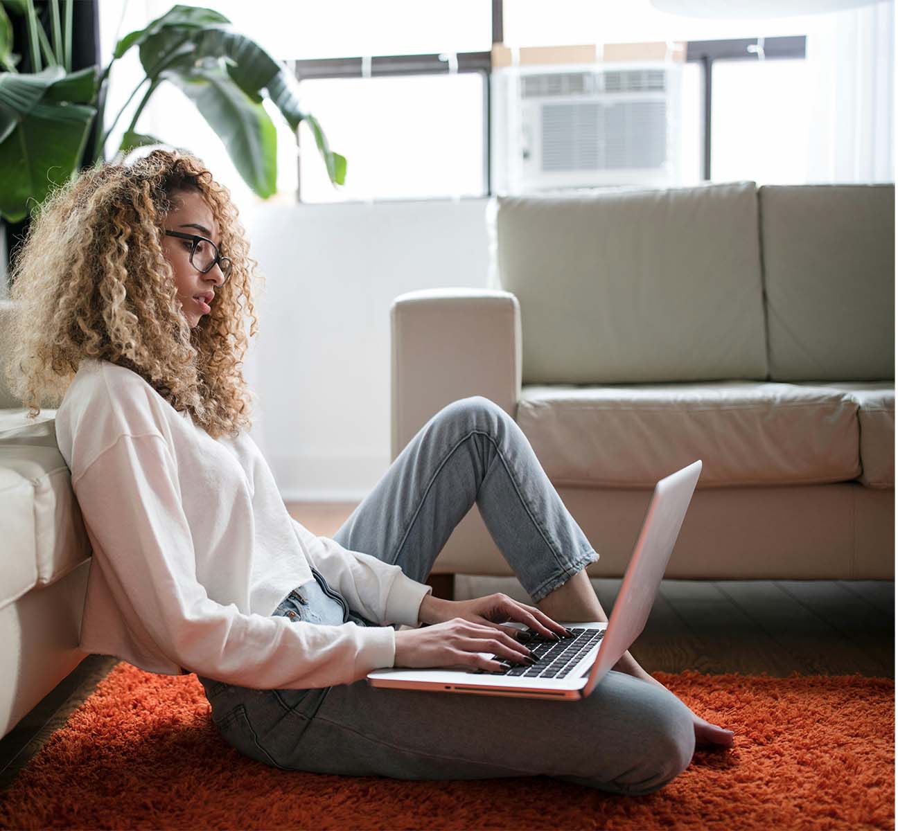 Person sitting on the floor relaxing while on a computer.